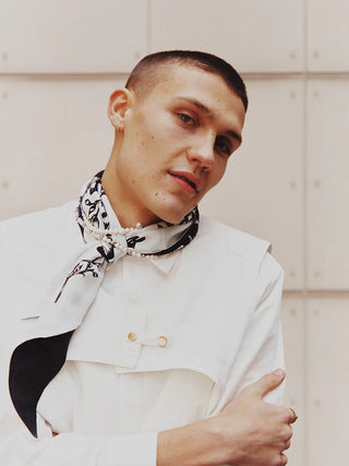 Man wearing monochrome black and white skinny silk scarf tied around neck