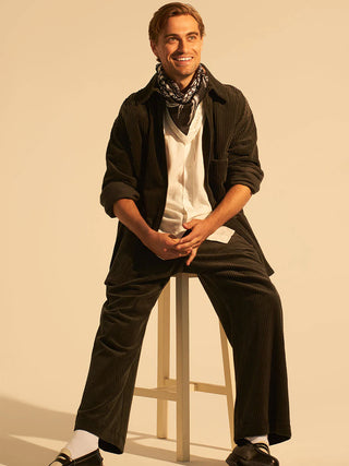 Trendy smiling man on stool wearing silk scarf in a wild spray coral pattern